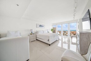 Une chambre moderne avec un grand lit, un bureau et une vue sur l’océan.