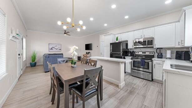 A modern kitchen with white cabinets, stainless steel appliances, and a wooden dining table. - Ground Floor Beach Side 2Min Walk To The Beach SF (South Padre Island)