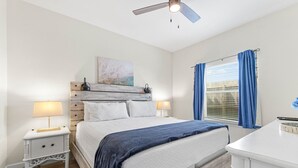 A bedroom with a bed, two bedside tables, a ceiling fan, a window with curtains, and a painting on the wall. - Ground Floor Beach Side 2Min Walk To The Beach SF (South Padre Island)