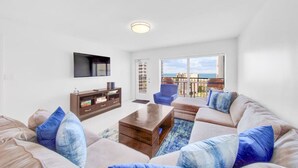 A modern living room with a sofa set, a coffee table, a TV mounted on the wall, and a view of the sea through large windows. - Amazing 7th floor beachfront condo wonderful views (South Padre Island)
