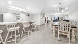 A modern kitchen with white cabinetry, a central island, and bar stools. - Amazing Saida beachfront 2 steps from amenities (South Padre Island)