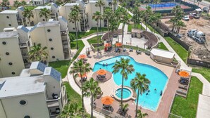 A resort with multiple buildings, a central swimming pool, and a view of the ocean.