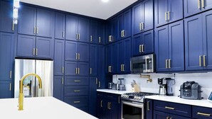 Une cuisine moderne avec des meubles bleu foncé, des appareils en acier inoxydable et des poignées dorées.