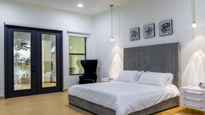 Une chambre moderne avec un grand lit, une chaise, une table de chevet et une fenêtre.