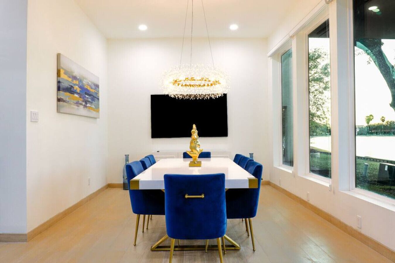 A dining area with a white table, blue chairs, and a chandelier.