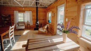 Ein gemütliches Blockhaus-Interieur mit Holzeinrichtung, Kamin, Essbereich und einem Fenster mit Aussicht.