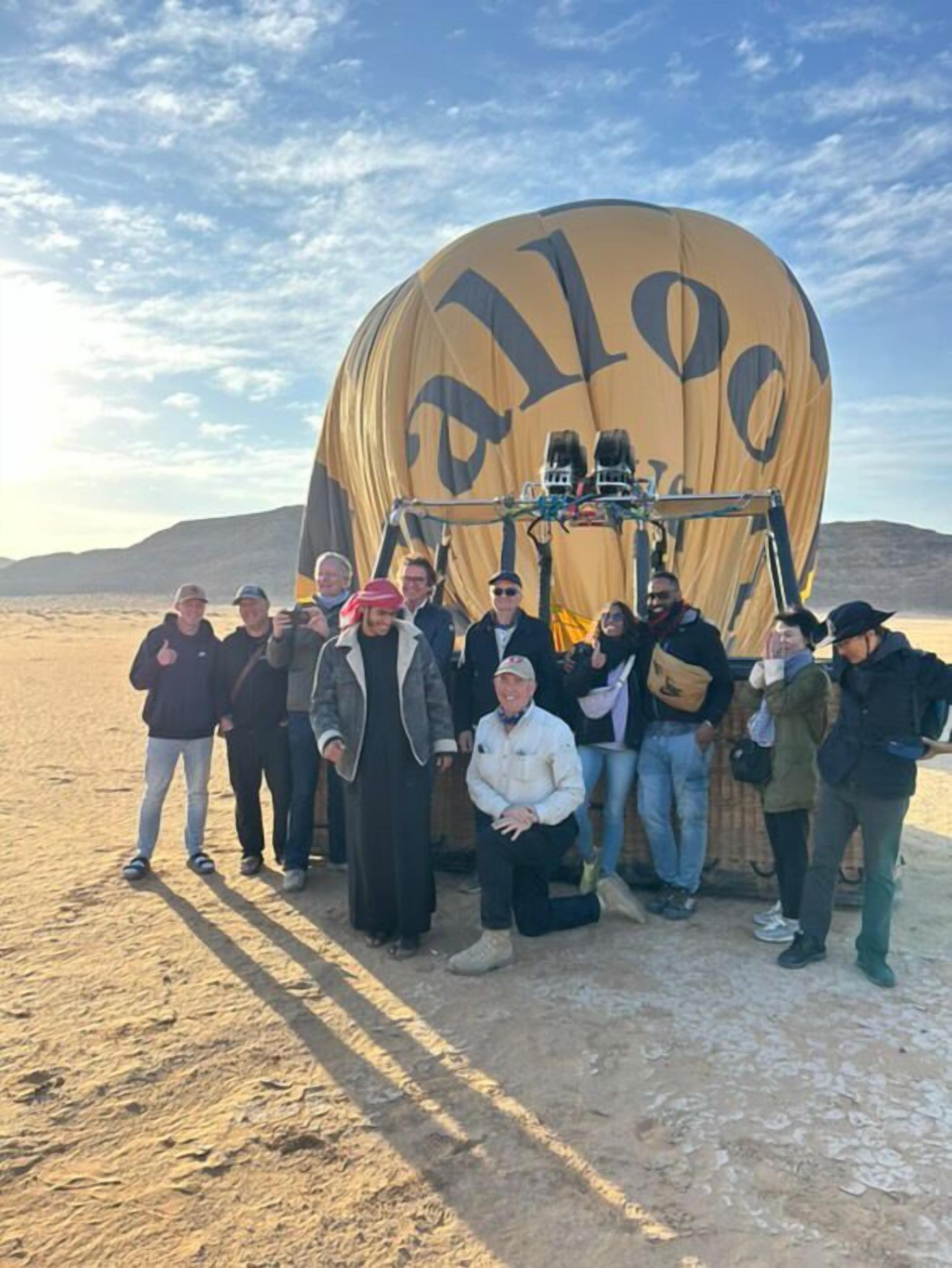 A group of people standing in front of a large hot air balloon with the word "allo" visible on it.