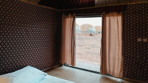 Una habitación con cama, ventana con cortinas y pared con diseño.