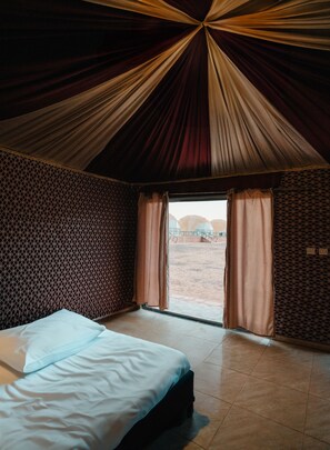 Experience the unique charm of this room, featuring a conical ceiling and a large bed against a patterned wall.