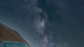 Varias tiendas en forma de cúpulas geodésicas bajo un cielo estrellado con la Vía Láctea visible.