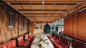 Un restaurante con una larga mesa dispuesta para una comida, rodeada de bancos rojos con estampado.