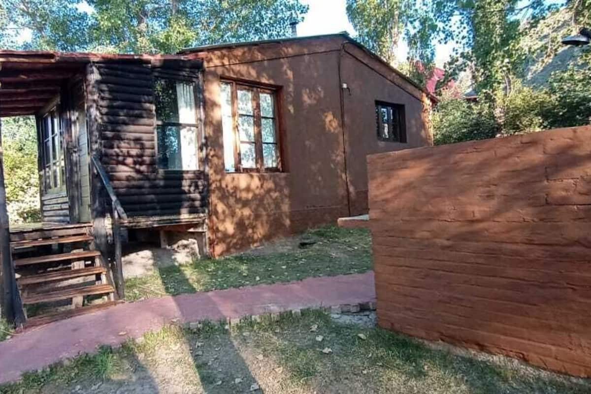 A rustic cabin with a wooden exterior, a porch, and a small window.