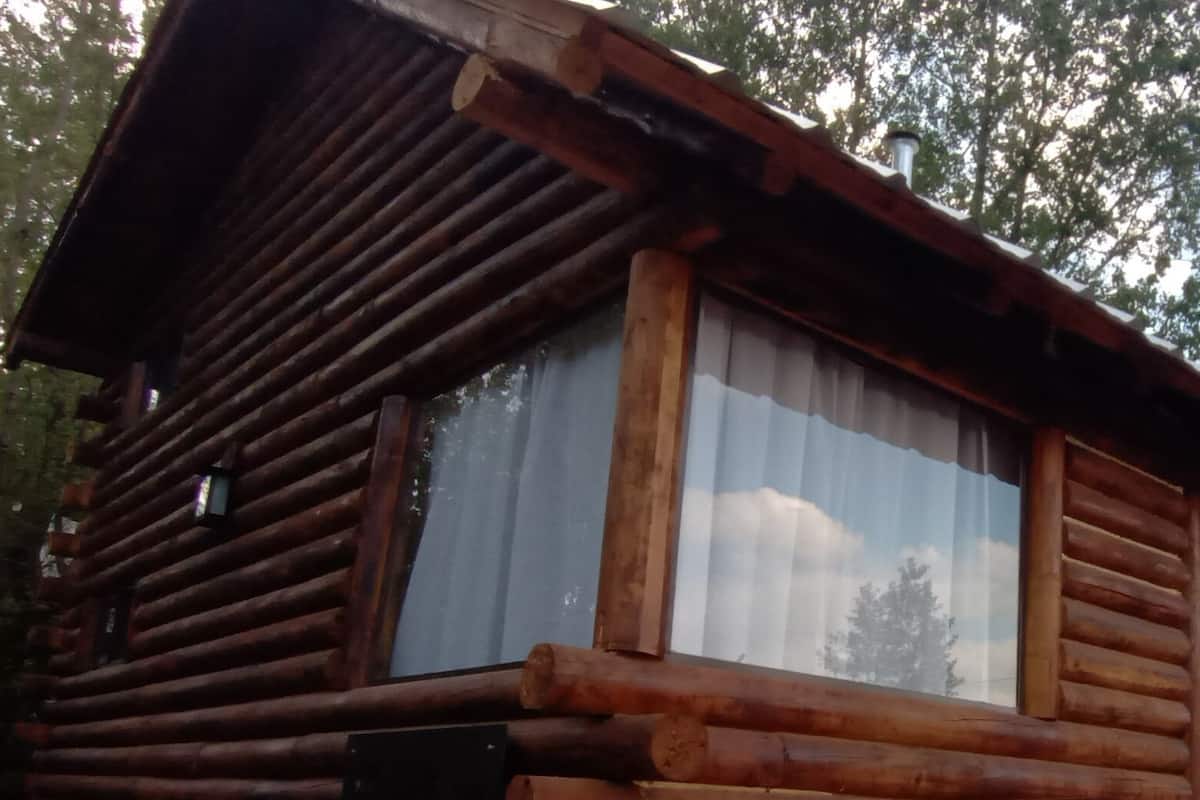 A wooden log cabin with large windows and a door.