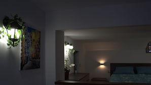 A bedroom with a bed, bedside table, and a wall-mounted lamp.