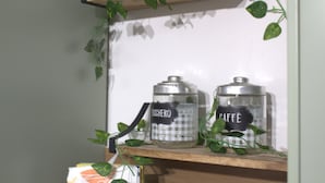 A shelf with two glass jars labeled "RICCHERO" and "CAFFÈ" and a plant.
