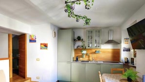 A compact kitchen with green cabinets, a wooden countertop, and a dining area with a table and chairs.