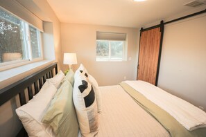 A bedroom with a bed, pillows, a window, and a sliding door.