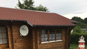 Un bâtiment en bois surmonté d’une antenne parabolique portant l’inscription « WISI ORBIT » et d’une maquette de phare.