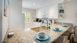 Una cocina moderna con armarios blancos, encimeras de granito y microondas integrado.