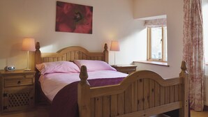 A bedroom with a wooden bed, two bedside tables, a nightstand, a window with a view, and a painting on the wall. - 2 bedroom accommodation in Oswestry (Oswestry)