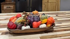 A kitchen with wooden cabinets, a black refrigerator, and a wooden door. - Rustic Acres Cabins (Dieterich)