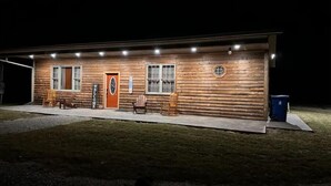 A log cabin with a welcoming sign, a front door, and a window. - Rustic Acres Cabins (Dieterich)