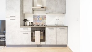 A modern kitchen with grey cabinets, a tiled backsplash, and stainless steel appliances. - Moscova Modern Apartment  (Milan)