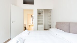A hotel room with a bed, a walk-in closet, and a small desk with a chair. - Moscova Modern Apartment  (Milan)