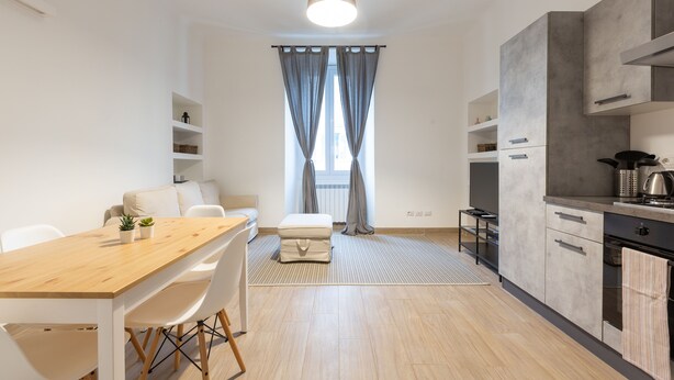 A modern kitchen with a wooden table, white chairs, and a grey sofa. - Moscova Modern Apartment  (Milan)