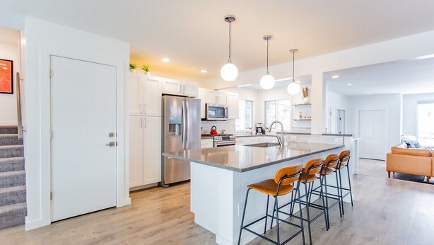 A modern kitchen with a central island, stainless steel appliances, and pendant lighting. - Bridger Hawk Duplex (NEW) (Bozeman)