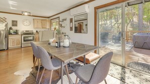A modern kitchen with wooden cabinets, a dining table with chairs, and a large window overlooking a deck. - Ruidoso Rental w/ Private Hot Tub: Walk to Midtown (Ruidoso)