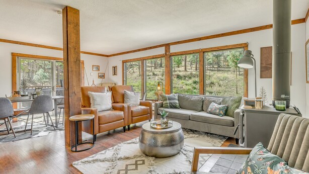 A spacious living room with a large window, a fireplace, and a cozy seating area. - Ruidoso Rental w/ Private Hot Tub: Walk to Midtown (Ruidoso)