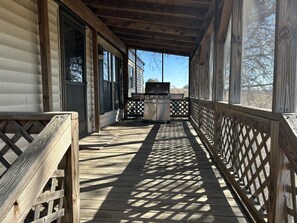 Una terraza cubierta de madera con una parrilla y vistas del entorno.