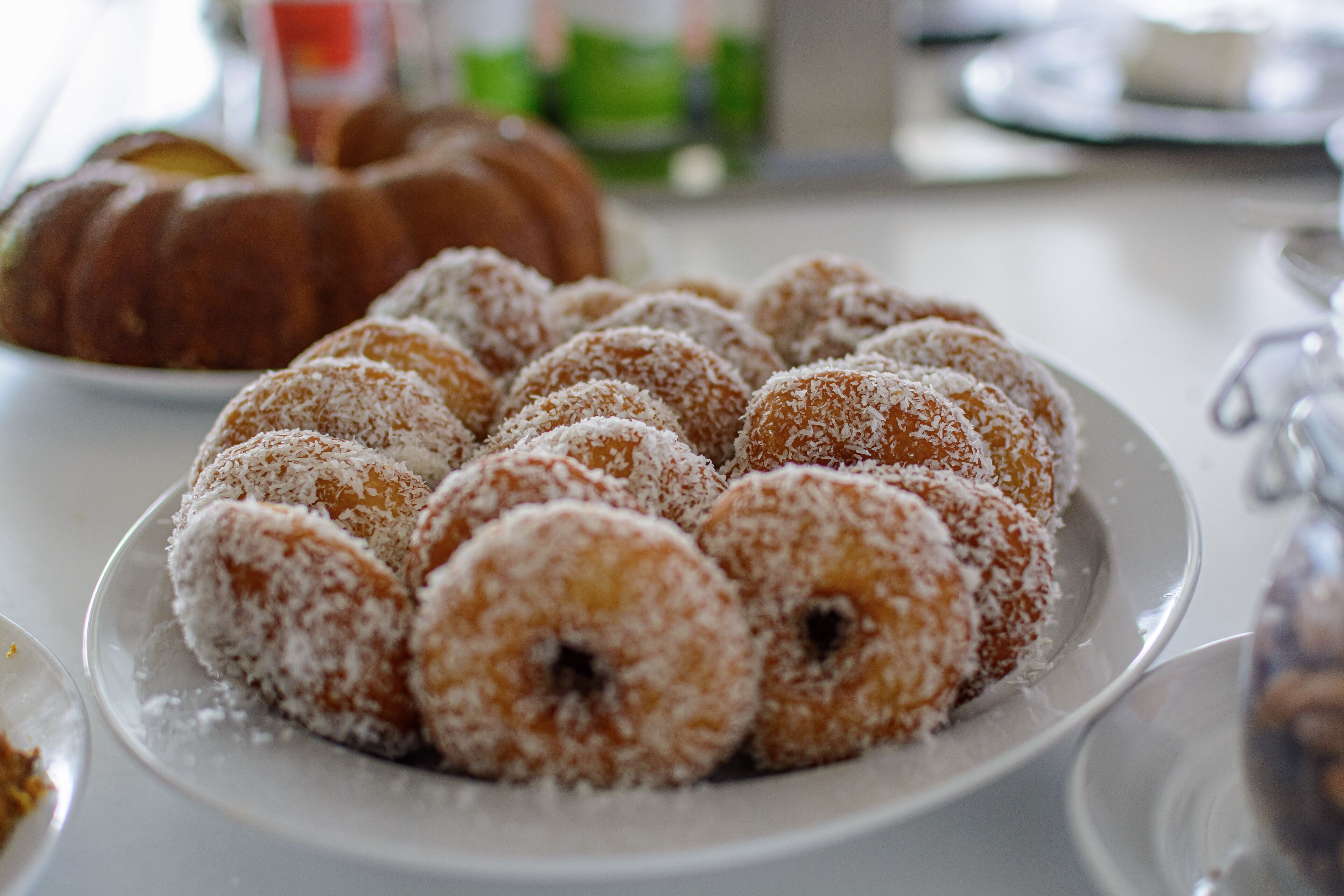 Un plat de rosquilles cobertes de coco damunt d'una taula blanca.