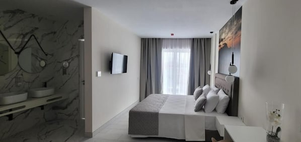 Une chambre d’hôtel moderne avec un mur en marbre, un lit doté d’une tête de lit grise, une table de chevet, une télévision et une fenêtre avec des rideaux.