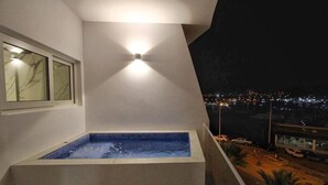 Een jacuzzi op een balkon met uitzicht op de stad 's nachts.