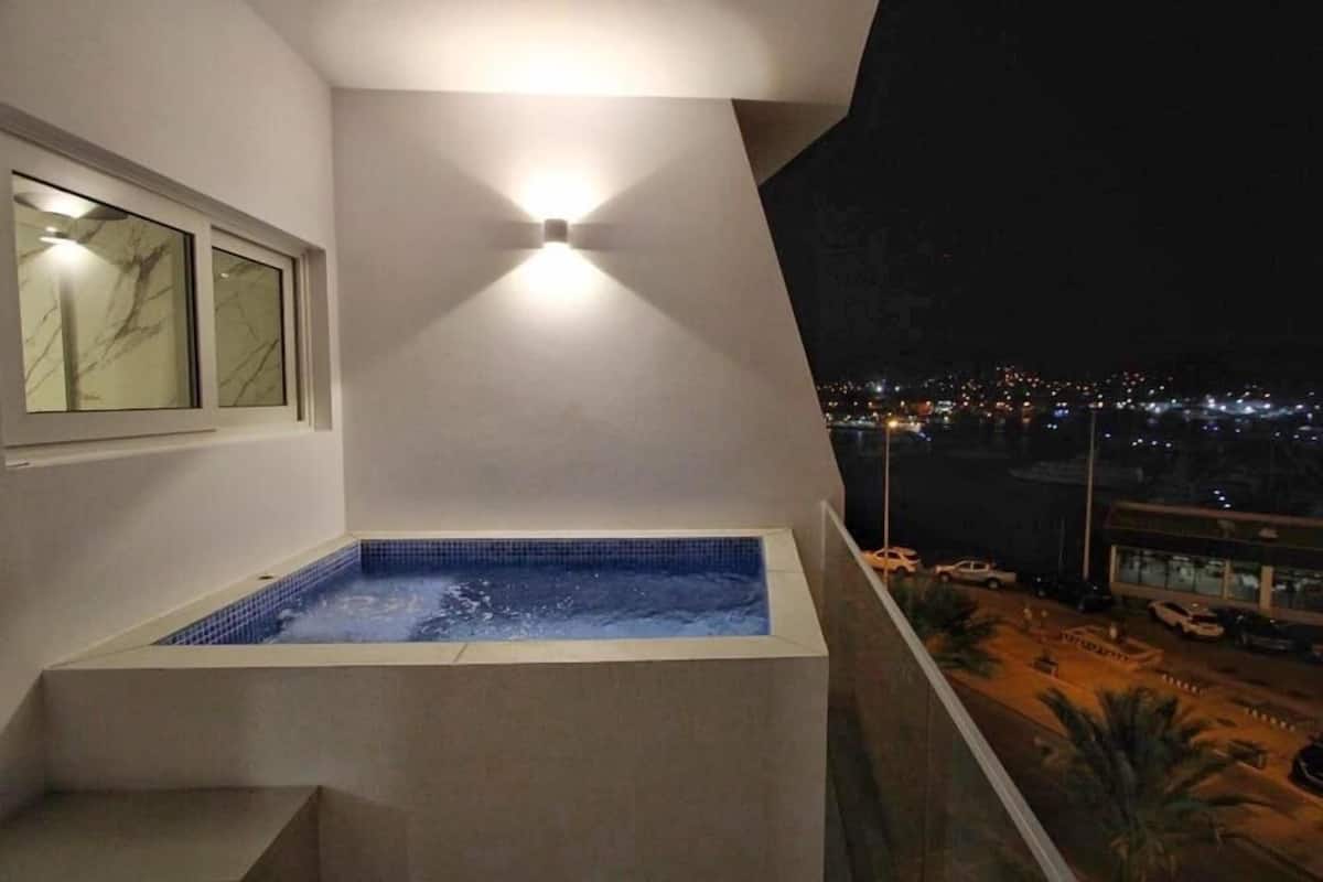 Een jacuzzi op een balkon met uitzicht op de stad 's nachts.