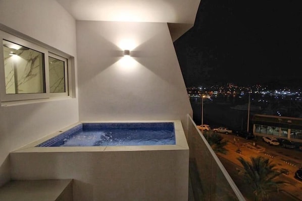 A hot tub on a balcony with a city view at night. - Ouril Hotel Mindelo (São Vicente)