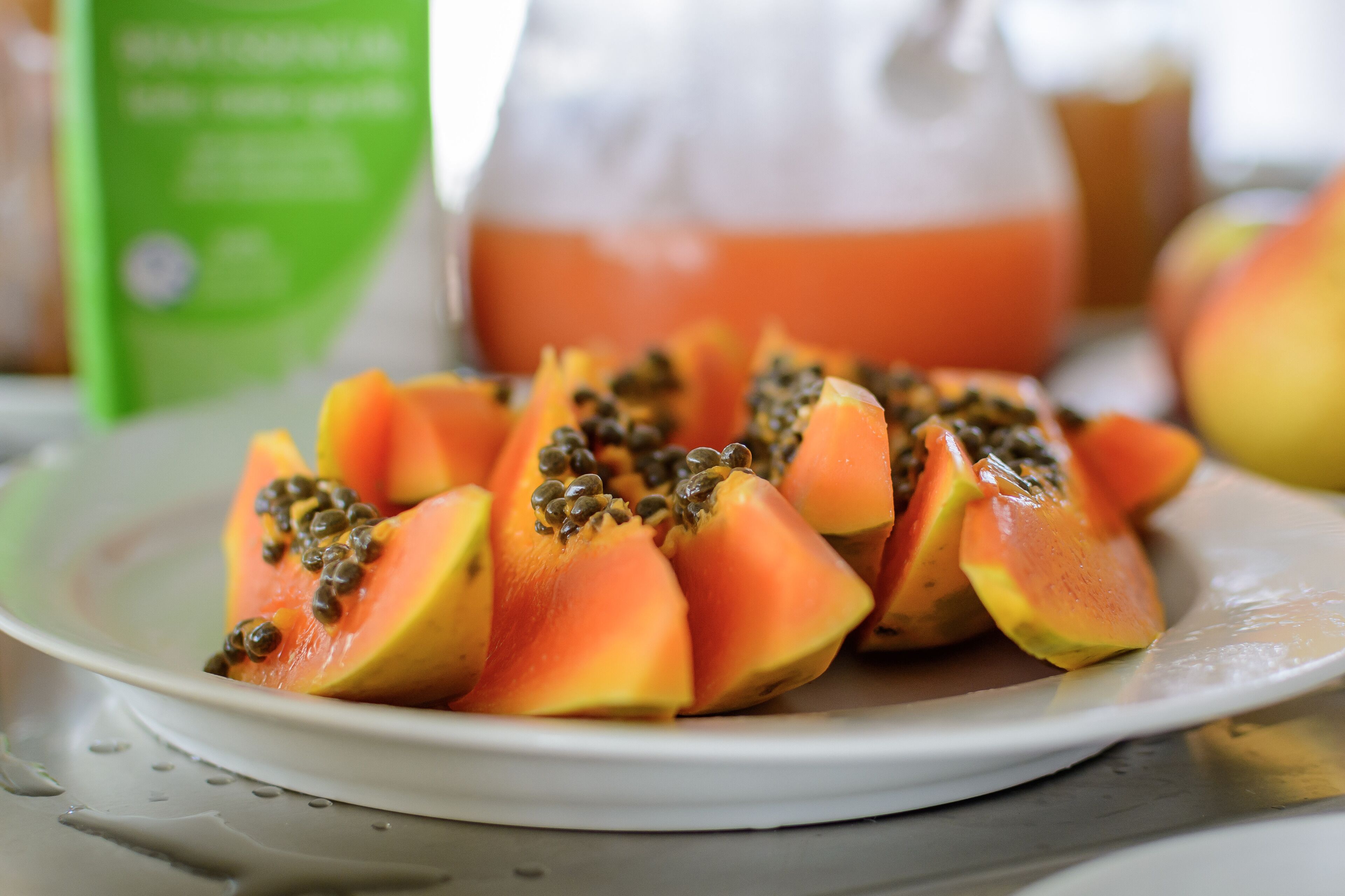 Un plato de papaya en rodajas con semillas sobre un plato blanco.