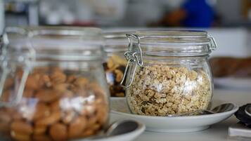 A breakfast buffet with various food items in glass jars, including granola and nuts, on white plates.