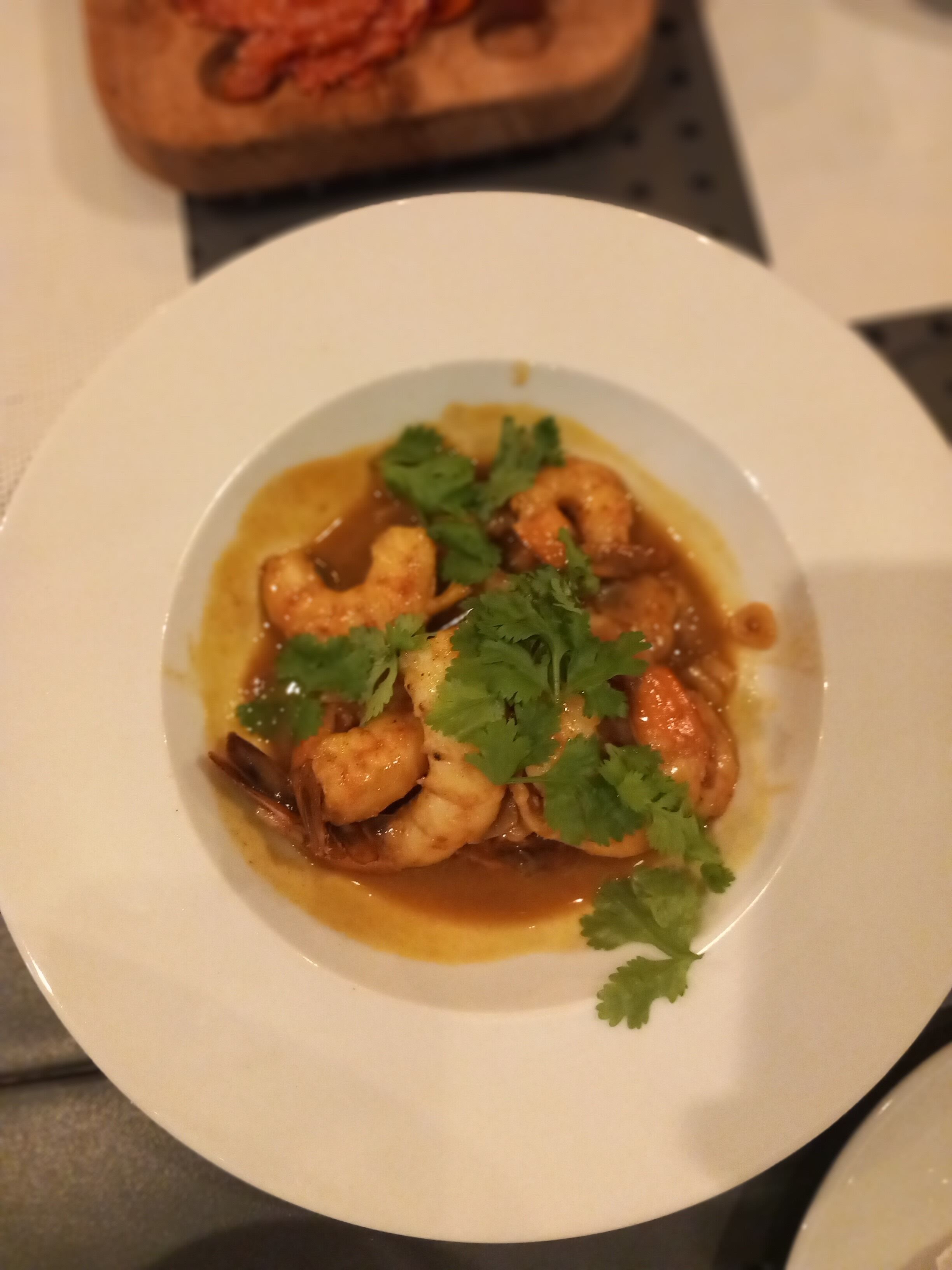 A white plate with a seafood dish garnished with cilantro.