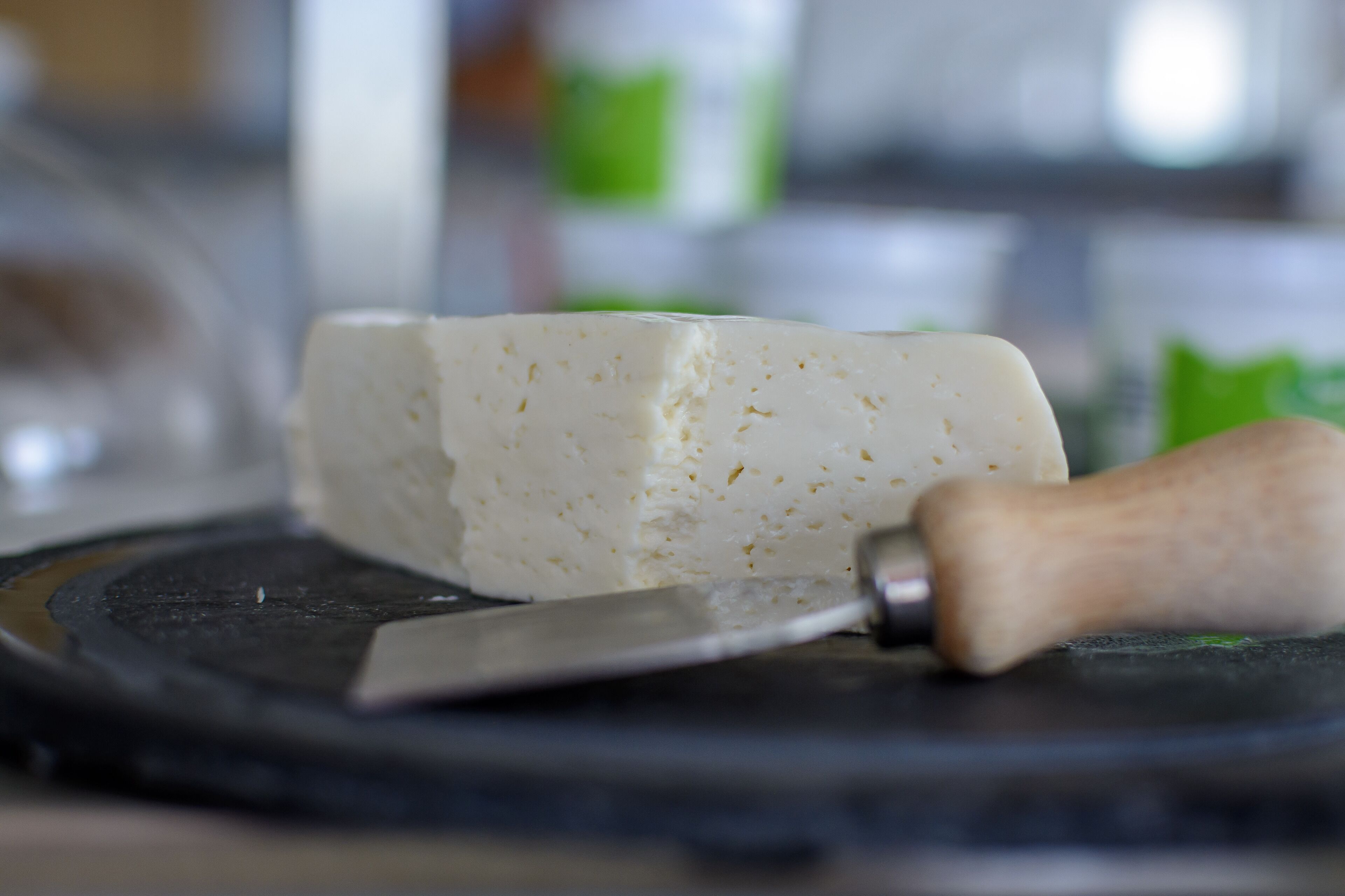 A block of cheese on a cutting board with a knife.