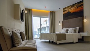 Een hotelkamer met een bed, een bank, een groot raam en een schilderij aan de muur.