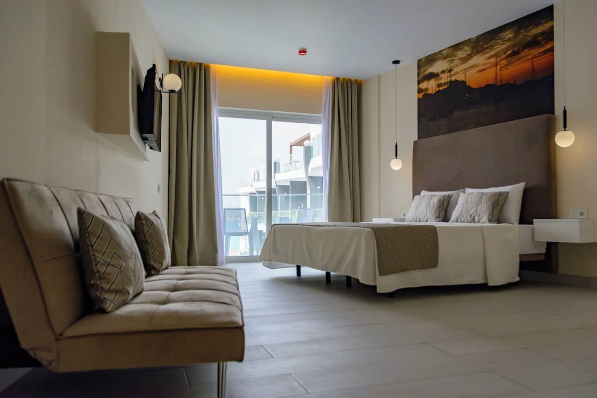 Een hotelkamer met een bed, een bank, een groot raam en een schilderij aan de muur.