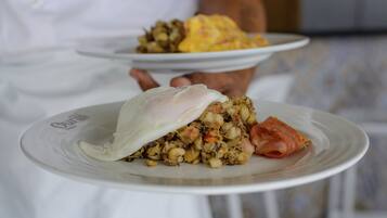 A person holding a plate with a dish that includes a poached egg and a mix of vegetables and meat.