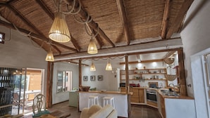 A spacious living area with a wooden ceiling, a central island with stools, and a kitchen area with wooden cabinets and a stove. - Casa Tarif - Bolonia Beach Campus, your beach house in Bolonia - Tarifa (Tarifa)