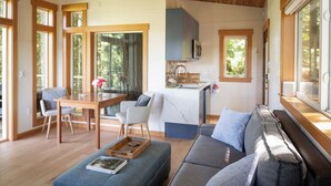 Una sala de estar moderna con techo de madera, un comedor con mesa y sillas, una cocina con encimera de mármol y ventanas amplias que aportan luz natural.