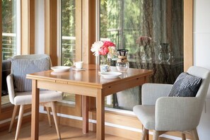 A dining area with a wooden table, two chairs, and a vase of flowers.