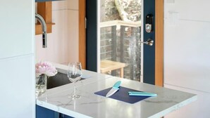 Una cocina compacta con encimera de mármol, una copa de vino y un cuaderno.