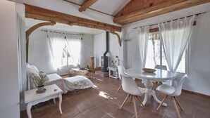 A cozy room with a wooden ceiling, a round dining table with chairs, a sofa, and a small table with a plant. - Bungalow - Bolonia Beach Campus Bolonia, your beach house (Tarifa)